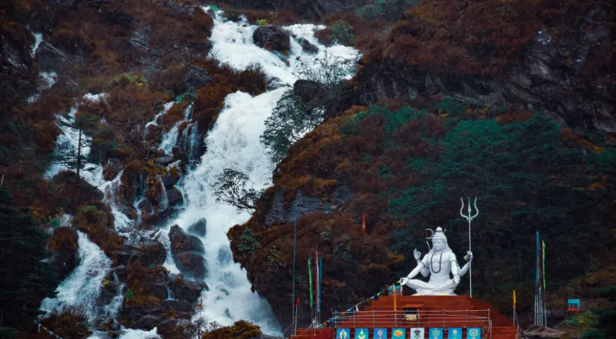A colorful gallery image of the holy Tsomgo Lake (Changu Lake) with a decorated yak and prayer flags fluttering against the Himalayan backdrop.